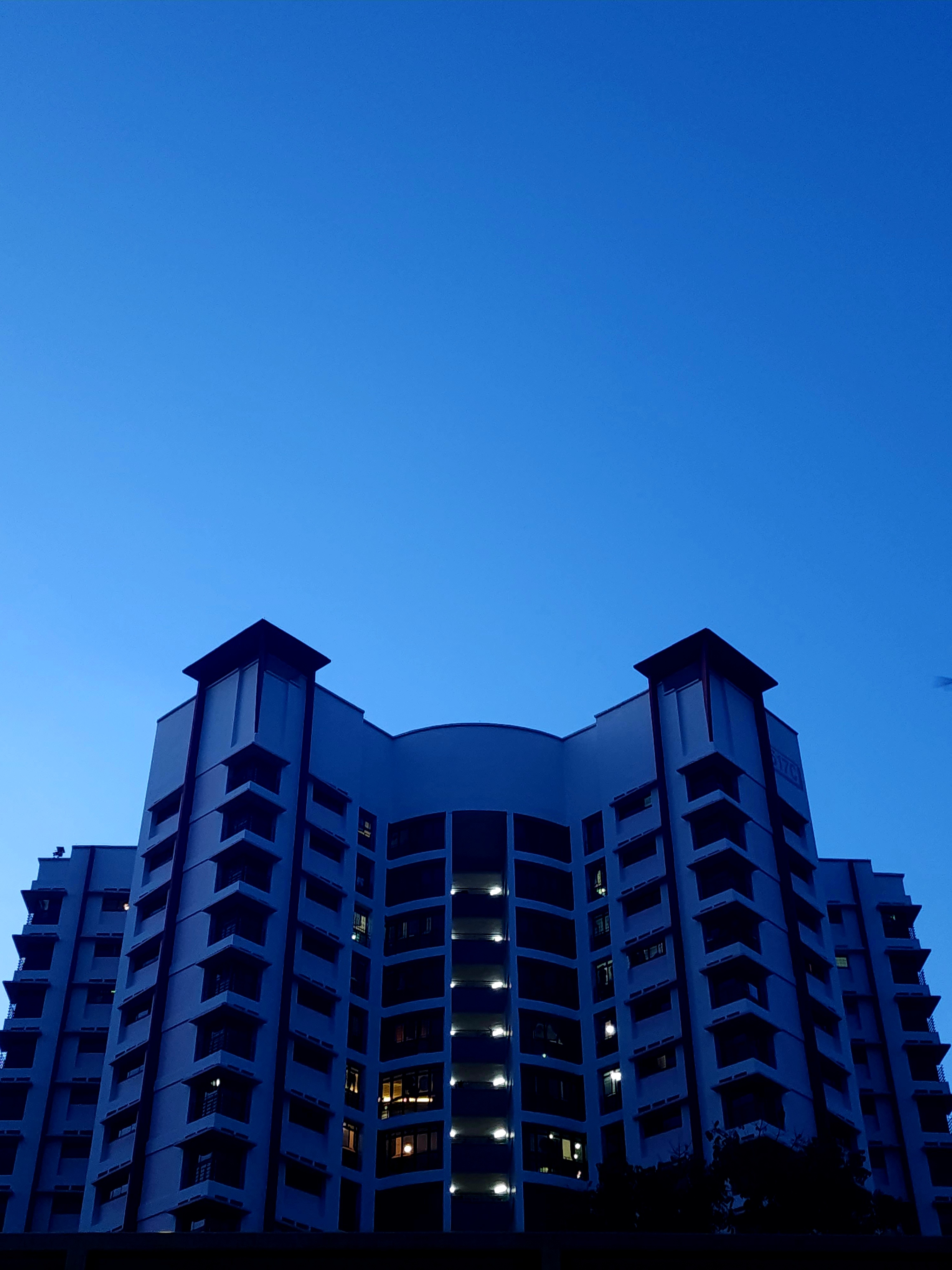 An apartment block silhouetted against a deep blue evening sky