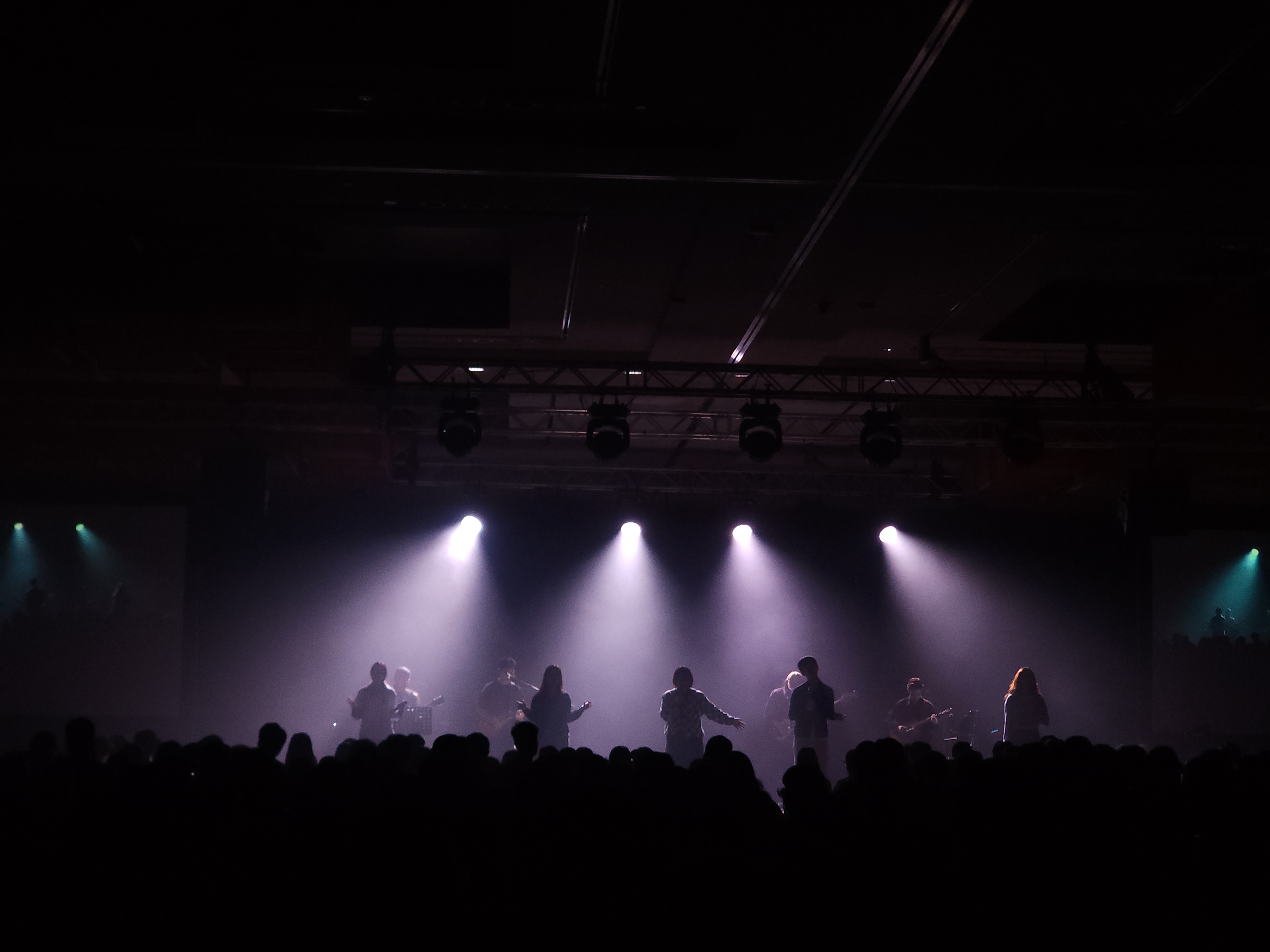Performers silhouetted beneath purple stage lights